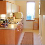 A modern kitchen with light wood cabinets, a stainless steel sink, and appliances.