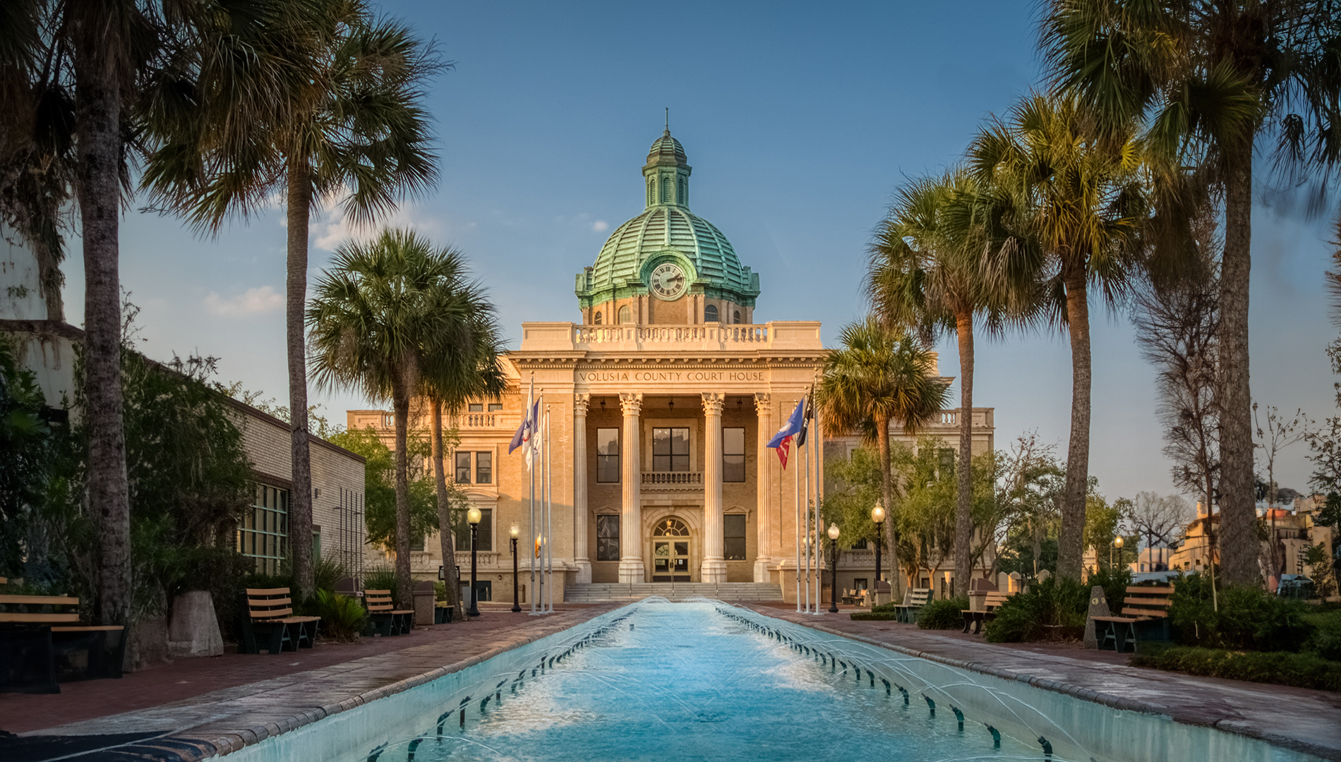 The image is a photograph of an outdoor swimming pool with a large, arched entryway and a building in the background.