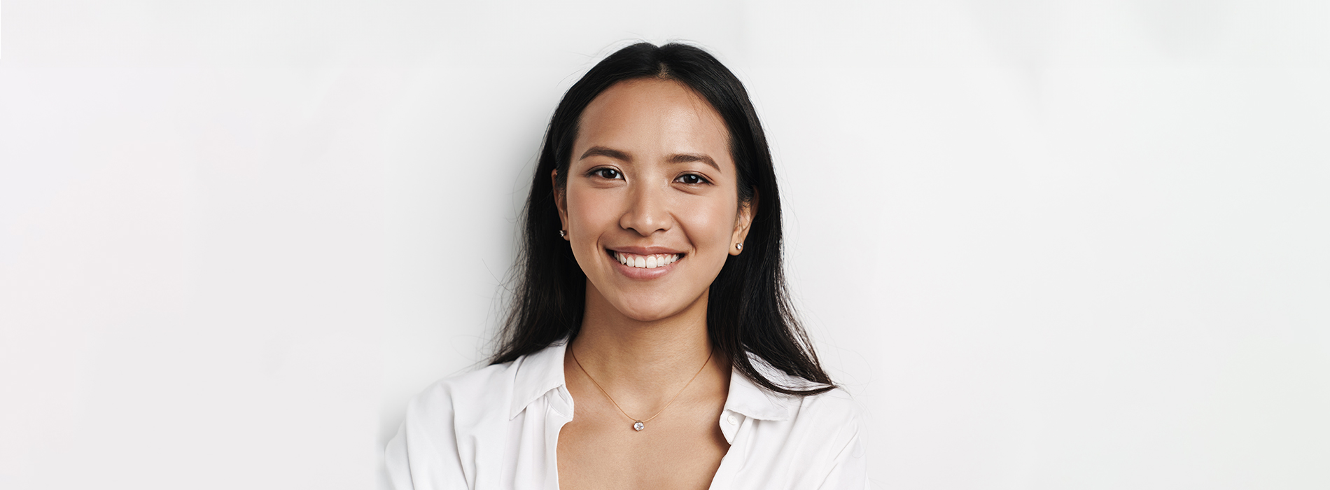 The image features a woman with a smiling expression, wearing a white top and standing against a plain background.