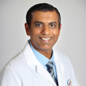 A man in a white lab coat, smiling and posing for the photo.