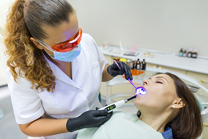 An image depicting a dental hygienist performing oral care on a patient using a dental drill.