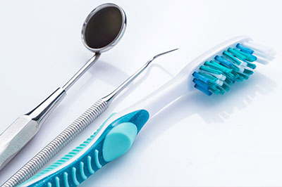 Dental tools, including a toothbrush and dental instruments, displayed on a white surface.