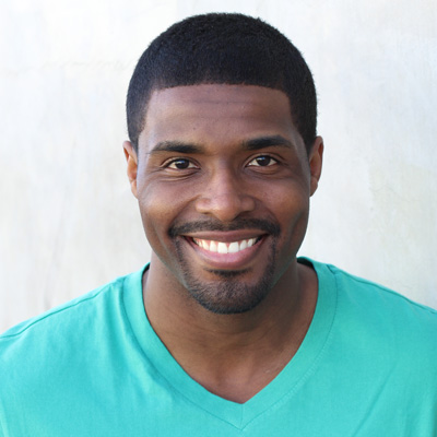An elderly couple posing for a photo with smiles, set against a backdrop of a sunset or sunrise.