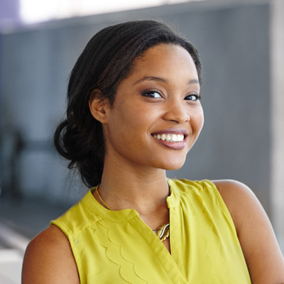Young woman with a radiant smile, posing for a portrait in a vibrant yellow top.
