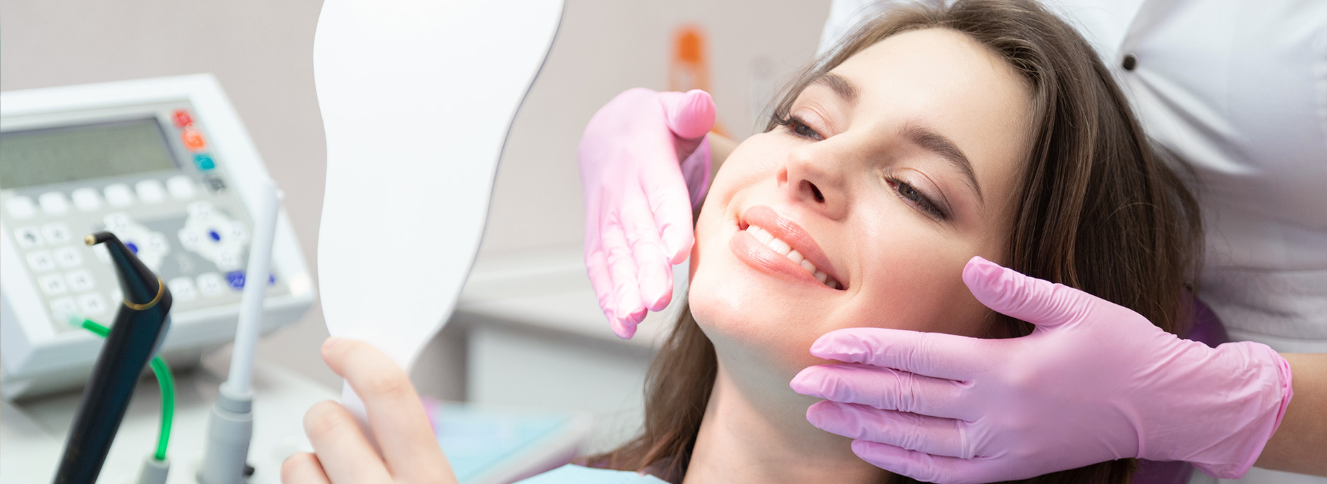 The image shows a woman seated in a dental chair, with her face covered by a dental mask, receiving dental treatment.