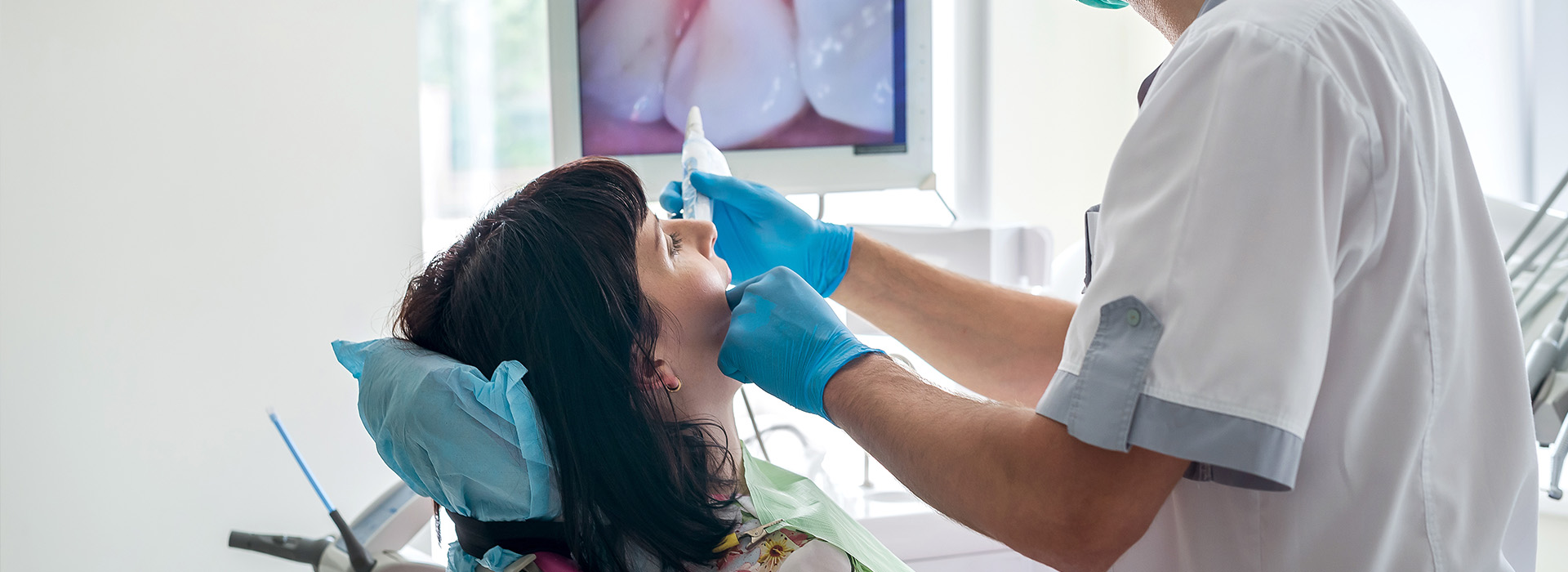 A dental professional performing a procedure on a patient, with a chair and various tools visible.