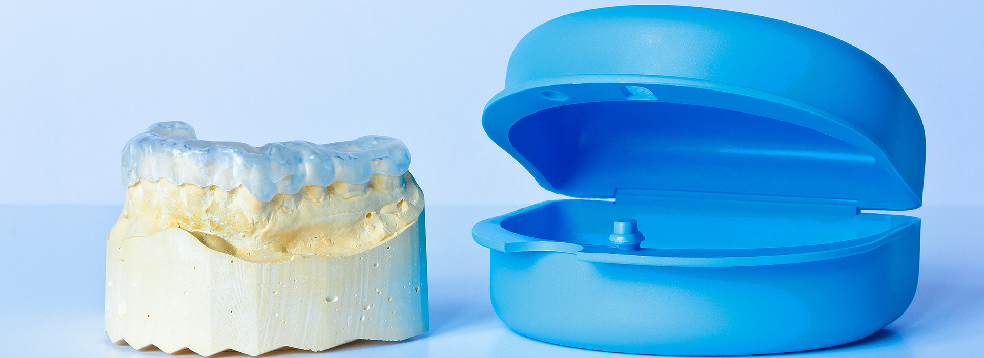 An image featuring a blue dental implant model on the left and a yellow dental implant model on the right.