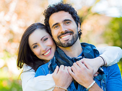 A man and a woman hugging, smiling, and posing for the photograph.