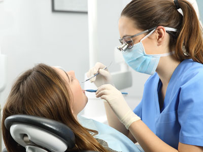 A dental hygienist is performing a cleaning procedure on a patient s teeth in an office setting.