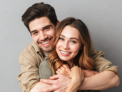 A young couple happily embracing each other in a portrait-style photograph.