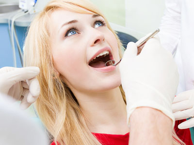 A woman receiving dental treatment, with a dental professional wearing gloves and performing the procedure.